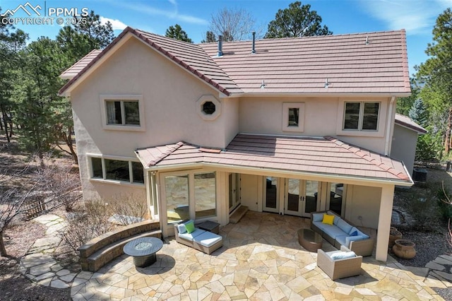 back of property with french doors, a patio area, stucco siding, and a tiled roof