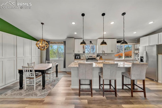 6465 Pawnee Cir, Colorado Springs, CO 80915 - kitchen with white cabinets, stainless steel appliances, a chandelier, and a wealth of natural light