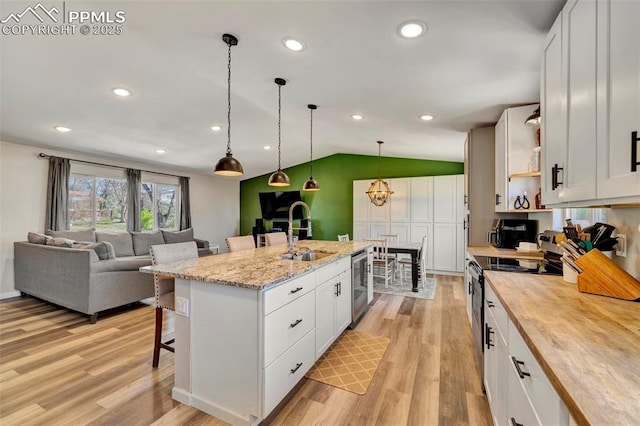 6465 Pawnee Cir, Colorado Springs, CO 80915 - kitchen with butcher block countertops, a breakfast bar area, a sink, light wood-style flooring, and vaulted ceiling