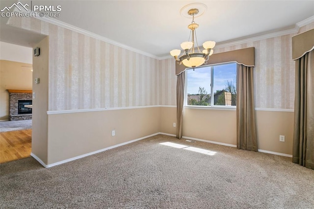 6675 Cabin Creek Dr, Colorado Springs, CO 80923 - carpeted spare room with a chandelier, ornamental molding, wallpapered walls, a glass covered fireplace, and baseboards