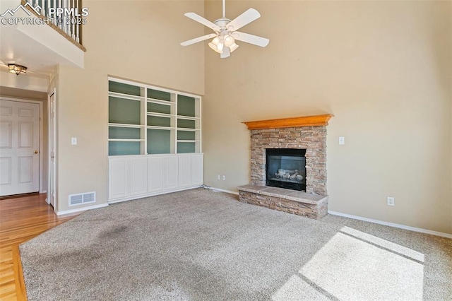 6675 Cabin Creek Dr, Colorado Springs, CO 80923 - unfurnished living room with a towering ceiling, baseboards, ceiling fan, a fireplace, and carpet flooring