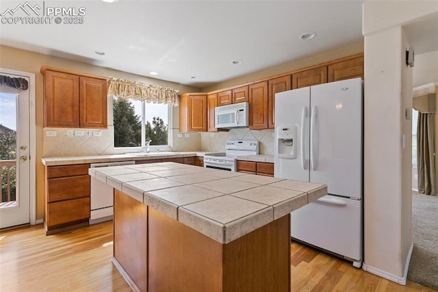 6675 Cabin Creek Dr, Colorado Springs, CO 80923 - kitchen with white appliances, tile counters, a sink, light wood-type flooring, and a center island