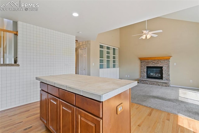 6675 Cabin Creek Dr, Colorado Springs, CO 80923 - kitchen featuring ceiling fan, tile countertops, light wood-style flooring, a fireplace, and vaulted ceiling