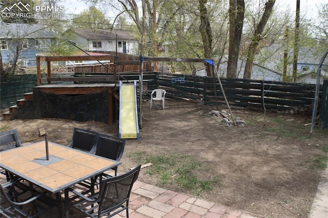 view of yard with fence, a patio area, outdoor dining area, and a playground