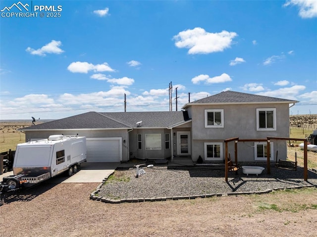 back of house featuring roof with shingles, stucco siding, an attached garage, and driveway