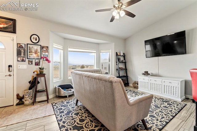 living room featuring baseboards, ceiling fan, wood finished floors, and vaulted ceiling