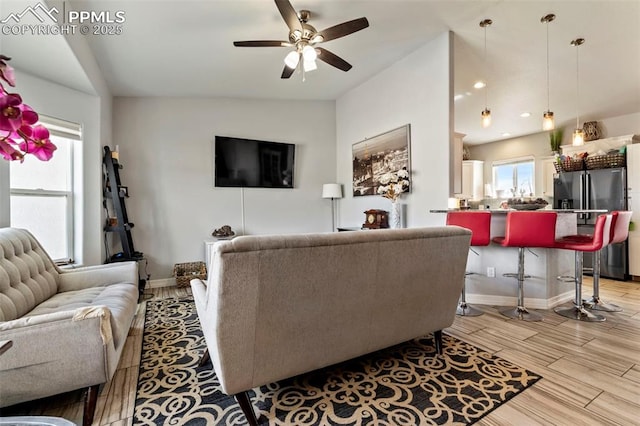 living area with ceiling fan, vaulted ceiling, baseboards, recessed lighting, and light wood-style flooring