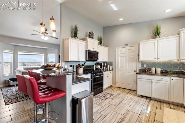 kitchen featuring decorative backsplash, a peninsula, a breakfast bar area, white cabinets, and appliances with stainless steel finishes