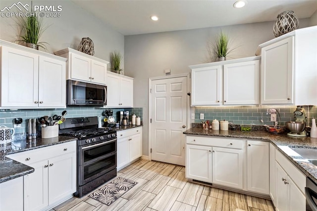 kitchen featuring decorative backsplash, stainless steel appliances, white cabinetry, and dark stone countertops