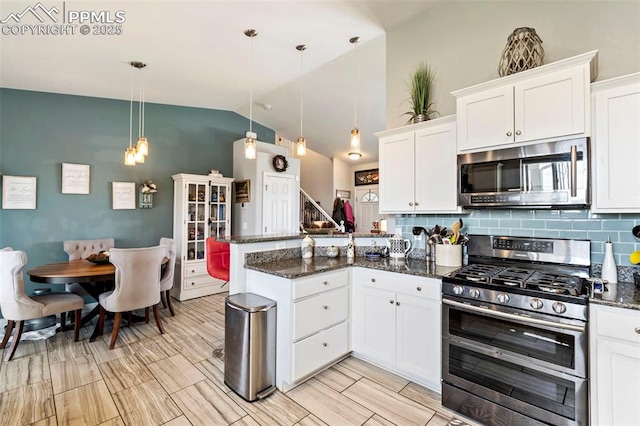 kitchen with appliances with stainless steel finishes, tasteful backsplash, vaulted ceiling, a peninsula, and white cabinetry