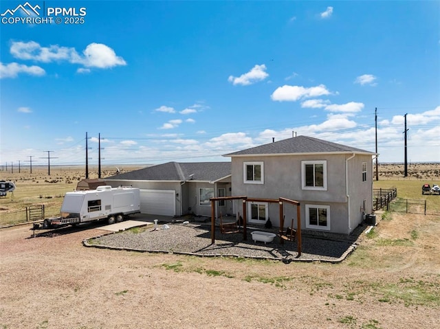 rear view of house featuring stucco siding, fence, driveway, and a garage