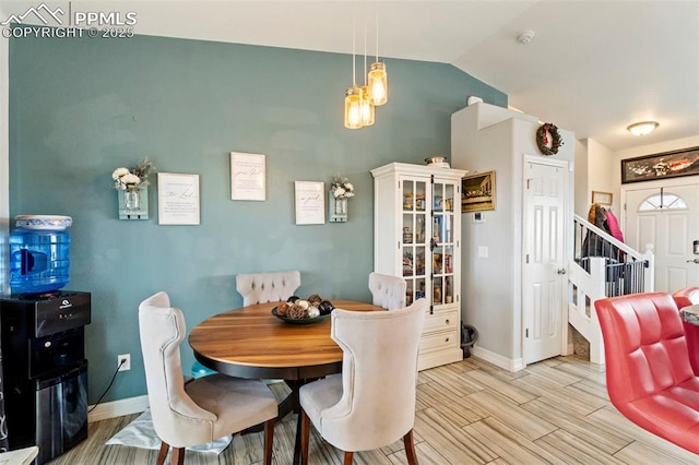 dining space with baseboards, vaulted ceiling, stairs, and wood finish floors
