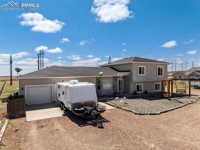 split level home featuring fence, an attached garage, concrete driveway, and stucco siding