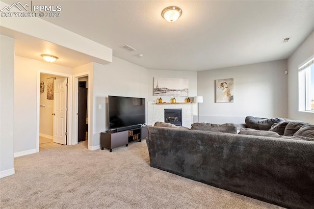living room featuring visible vents, baseboards, a glass covered fireplace, and light carpet