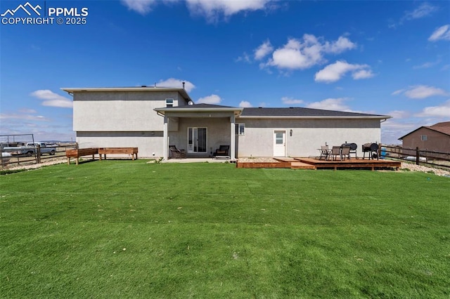 back of house with fence, stucco siding, a lawn, and a deck