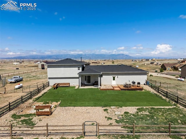 rear view of property with a lawn, a wooden deck, a gate, a fenced backyard, and a rural view