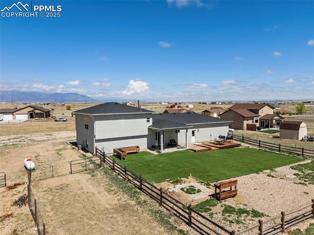 rear view of property with a fenced backyard, stucco siding, a yard, and a shingled roof