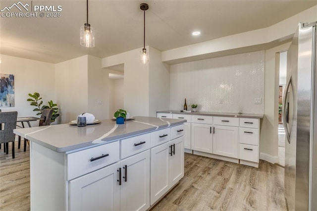 1120 Lake Woodmoor Dr, Monument, CO 80132 - kitchen with light wood finished floors, pendant lighting, freestanding refrigerator, and white cabinets