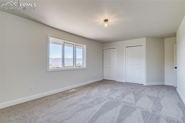 1120 Lake Woodmoor Dr, Monument, CO 80132 - unfurnished bedroom featuring visible vents, baseboards, multiple closets, and carpet floors