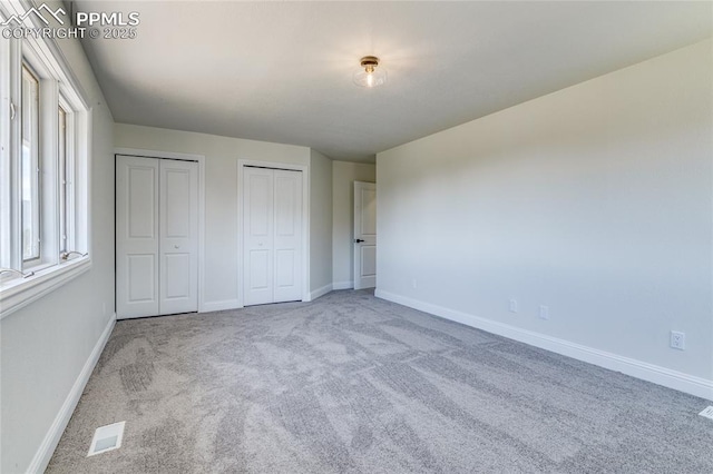 1120 Lake Woodmoor Dr, Monument, CO 80132 - unfurnished bedroom with visible vents, baseboards, carpet flooring, and two closets
