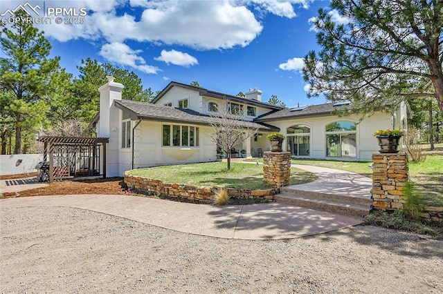 17350 Goshawk Rd, Colorado Springs, CO 80908 - mediterranean / spanish-style house with a pergola, a chimney, stucco siding, and a front yard