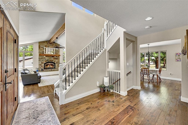 17350 Goshawk Rd, Colorado Springs, CO 80908 - foyer entrance featuring vaulted ceiling with beams, a stone fireplace, hardwood / wood-style floors, and a wealth of natural light