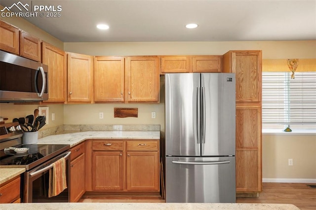 kitchen featuring appliances with stainless steel finishes, light stone countertops, recessed lighting, and light wood-style flooring