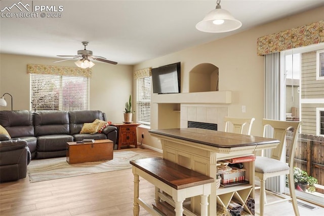 living room featuring a healthy amount of sunlight, a ceiling fan, and a tile fireplace