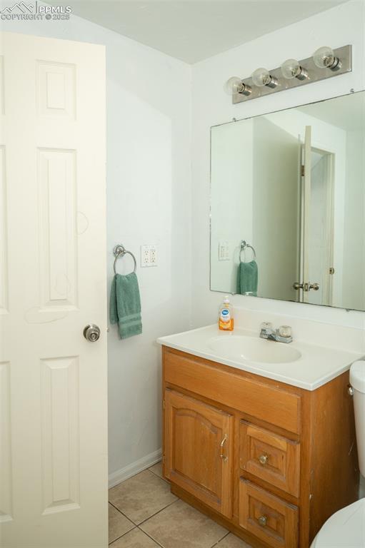 1015 5th St, Del Norte, CO 81132 - half bath with tile patterned flooring, toilet, vanity, and baseboards