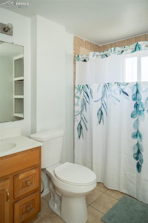 1015 5th St, Del Norte, CO 81132 - full bath with tile patterned floors, vanity, a shower with shower curtain, and toilet