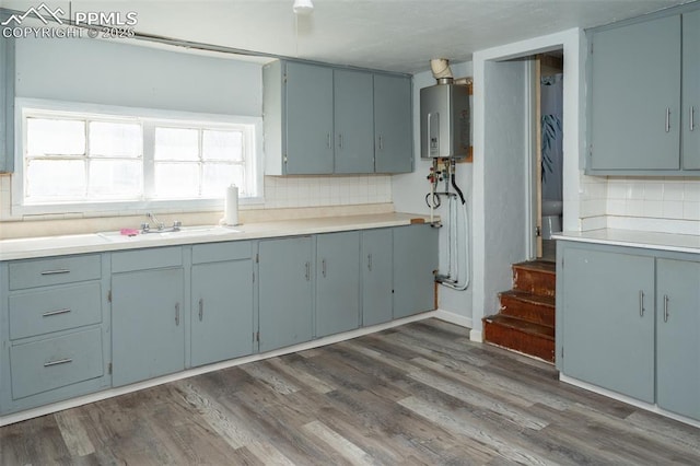 1015 5th St, Del Norte, CO 81132 - kitchen with dark wood-style floors, a sink, decorative backsplash, water heater, and light countertops