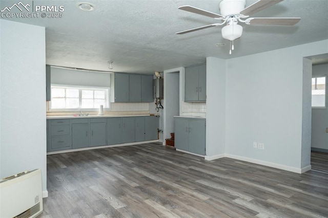 1015 5th St, Del Norte, CO 81132 - interior space with ceiling fan, water heater, dark wood finished floors, backsplash, and gray cabinetry