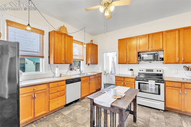 kitchen featuring light countertops, a ceiling fan, a sink, hanging light fixtures, and appliances with stainless steel finishes