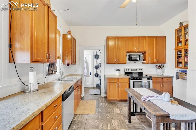 kitchen with brown cabinetry, stainless steel appliances, light countertops, and a sink