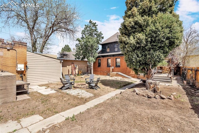 back of house with fence, an outdoor fire pit, and a deck