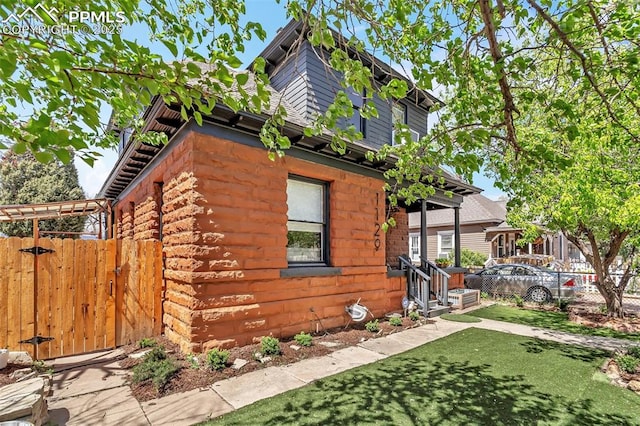 view of side of property featuring a lawn, a gate, and fence