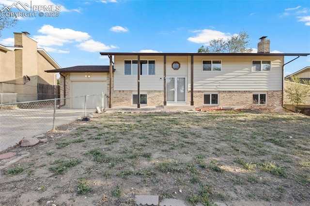 621 Rowe Ln, Colorado Springs, CO 80911 - split foyer home with fence, brick siding, an attached garage, a chimney, and driveway