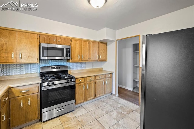 621 Rowe Ln, Colorado Springs, CO 80911 - kitchen with baseboards, light countertops, brown cabinetry, decorative backsplash, and stainless steel appliances