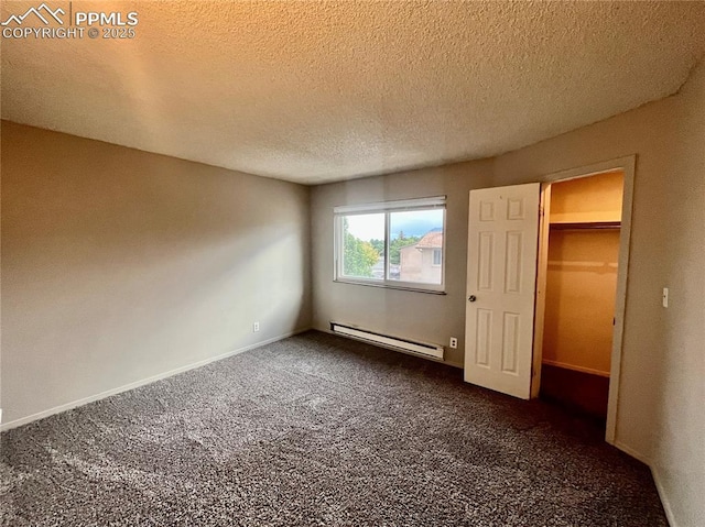 1154 Darby St, Colorado Springs, CO 80907 - unfurnished bedroom featuring baseboard heating, dark colored carpet, a textured ceiling, a walk in closet, and baseboards