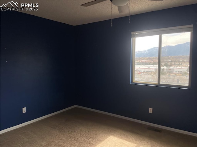 1426 Territory Trl, Colorado Springs, CO 80919 - empty room featuring a mountain view, a textured ceiling, a ceiling fan, carpet floors, and visible vents