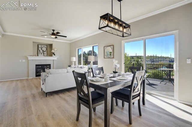 5717 Stable Ct, Colorado Springs, CO 80920 - dining space with ornamental molding, light wood-style floors, a ceiling fan, a tile fireplace, and baseboards