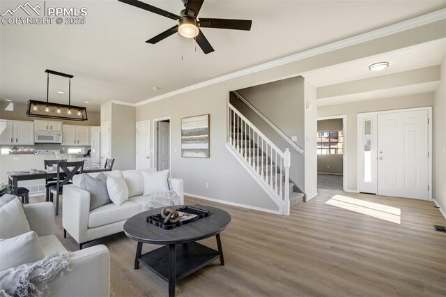 5717 Stable Ct, Colorado Springs, CO 80920 - living room featuring stairs, wood finished floors, ceiling fan, baseboards, and crown molding