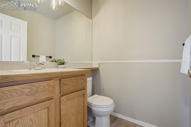 5717 Stable Ct, Colorado Springs, CO 80920 - half bathroom with vanity, baseboards, toilet, and wood finished floors
