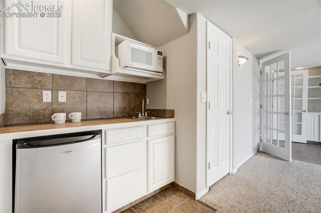 5717 Stable Ct, Colorado Springs, CO 80920 - kitchen featuring white microwave, a sink, refrigerator, backsplash, and white cabinetry