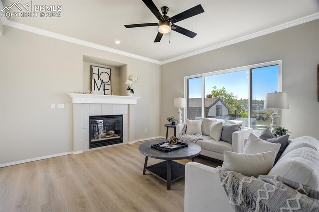 5717 Stable Ct, Colorado Springs, CO 80920 - living room with ceiling fan, crown molding, light wood-style floors, baseboards, and a tile fireplace