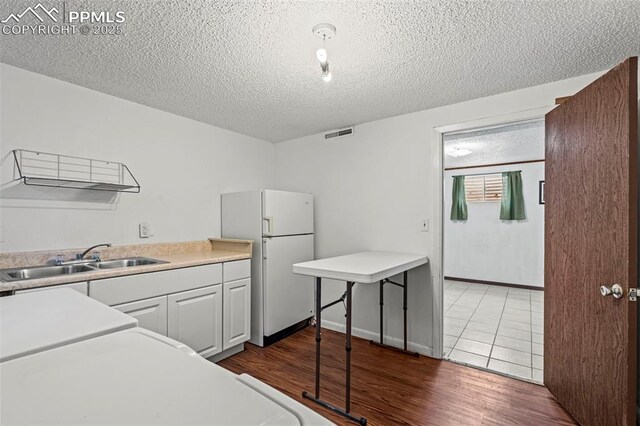 930 Bowser Dr, Colorado Springs, CO 80909 - kitchen with a sink, freestanding refrigerator, dark wood-style flooring, a textured ceiling, and light countertops