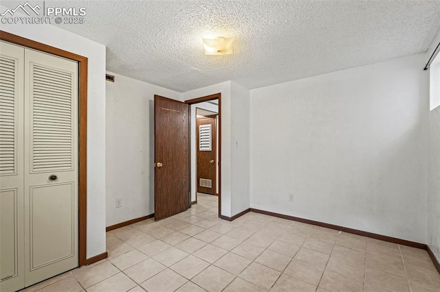 930 Bowser Dr, Colorado Springs, CO 80909 - unfurnished bedroom featuring a closet, a textured ceiling, baseboards, and light tile patterned floors