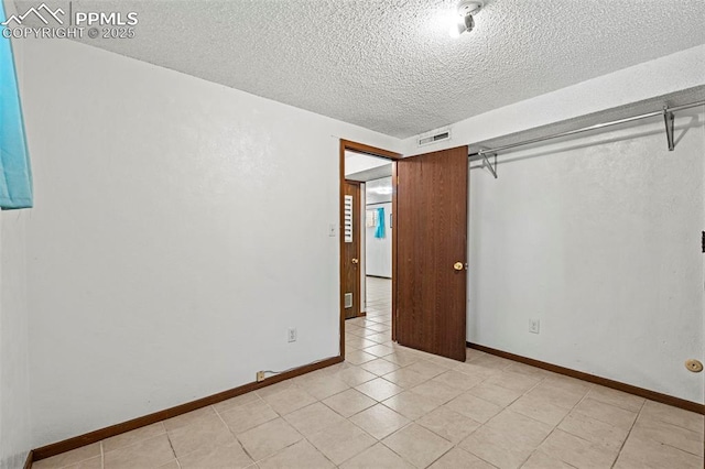 930 Bowser Dr, Colorado Springs, CO 80909 - unfurnished bedroom with a textured ceiling, light tile patterned floors, and baseboards