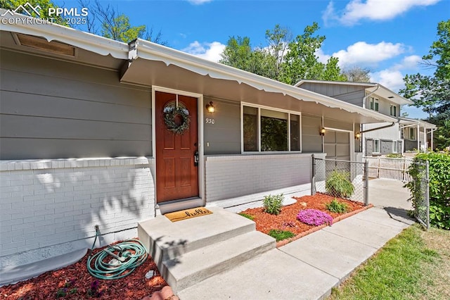 930 Bowser Dr, Colorado Springs, CO 80909 - doorway to property featuring brick siding, a garage, and concrete driveway