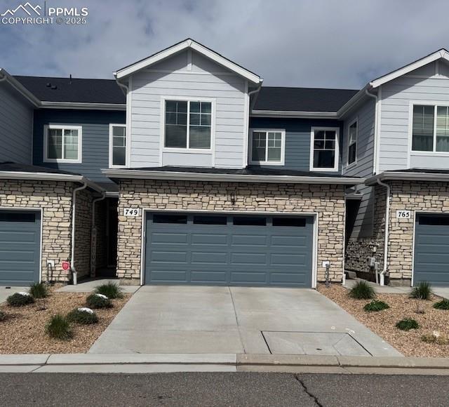 view of front of property featuring a garage, driveway, and stone siding
